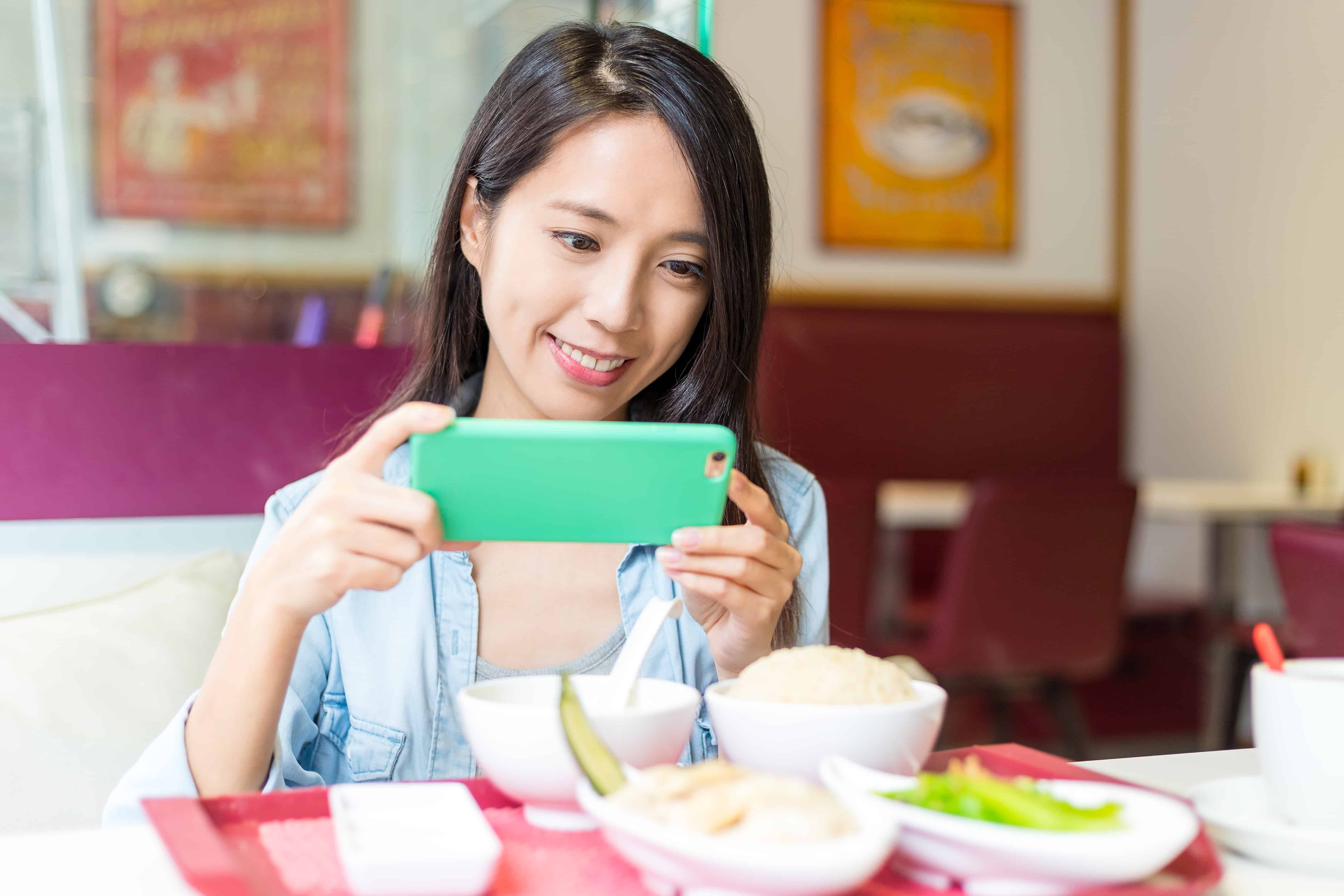 Woman taking photo on her dish in restaurant